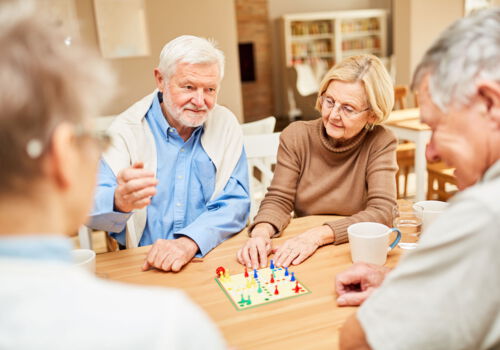 Seniorengruppe beim gemeinsamen Brettspiel im Aufenthaltsraum einer Einrichtung der Krüger-Gruppe